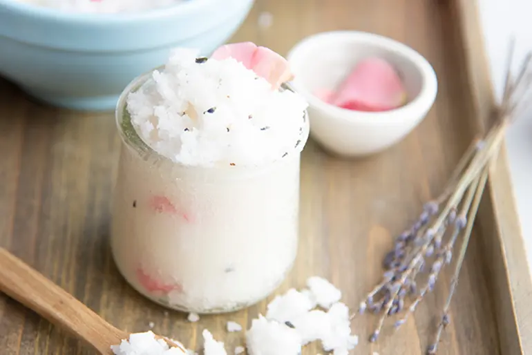 Pink salt bath rub in a Oui by Yoplait yogurt jar accompanied by lavender.