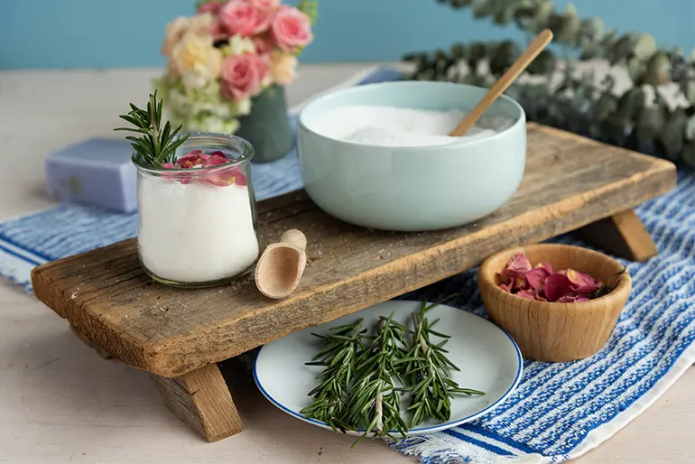 Salt in a Oui by Yoplait yogurt jar with a bowl of salt next to it as well as some fresh herbs.