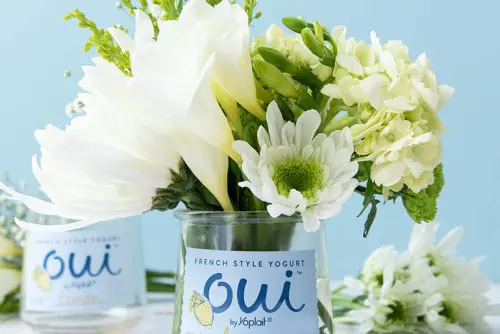 A close up of a Oui by Yoplait yogurt jar with flowers in it.
