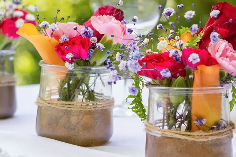 Two Oui by Yoplait yogurt jars on a table filled with flowers.