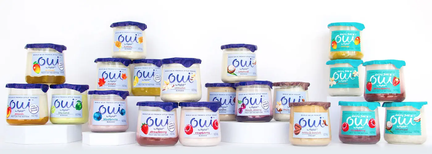 A collection of Oui by Yoplait yogurt products some placed on pedestals and some sit below.