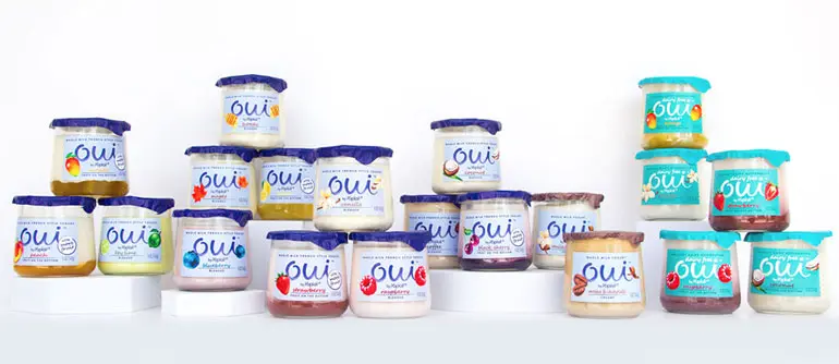 A collection of Oui by Yoplait yogurt products some placed on pedestals and some sit below.
